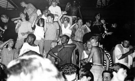 Dansende menigte tijdens een donkere, vroege rave in een loods