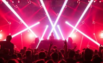 DJ draait voor een dansende menigte onder felle rode en witte lichten