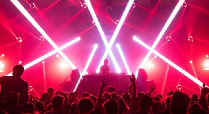 DJ draait voor een dansende menigte onder felle rode en witte lichten